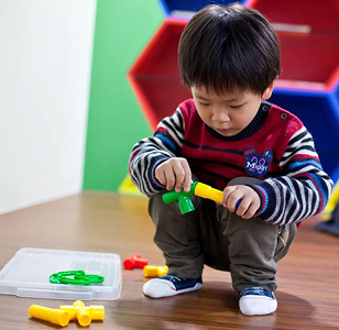 A young boy playing with colorful toy tools indoors.