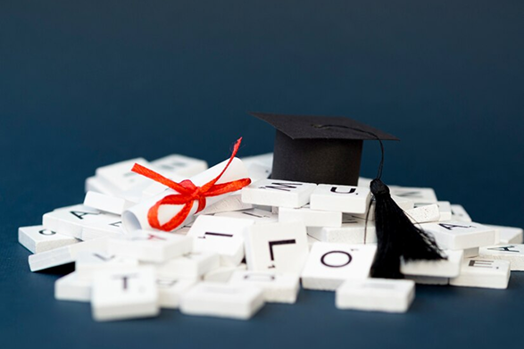 Graduation cap and diploma on letter tiles symbolizing education.