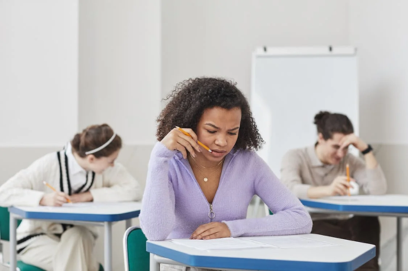 A student concentrating on her exam in a classroom.