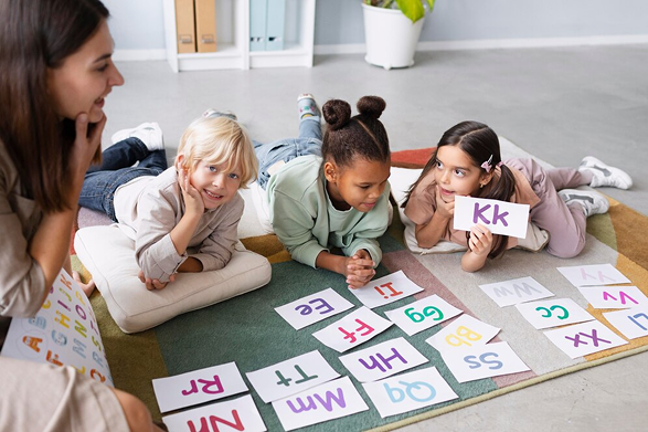 Three children lying on the floor practicing reading with flashcards.