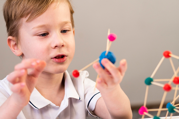 A young boy engaging with a colorful molecular model.