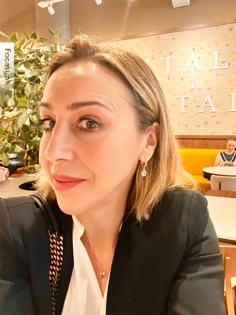 A woman with blonde hair in a black top sitting in a cozy cafe.