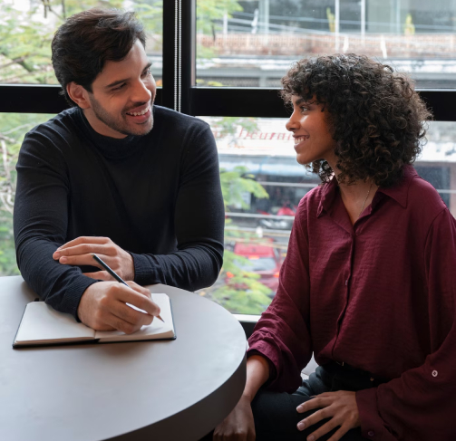 Two colleagues sharing a joyful conversation at a cafe table.
