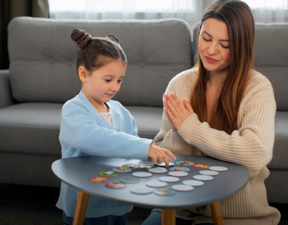 A mother and daughter playing a card game together at a table.